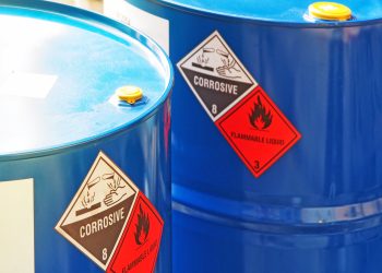 the close-up shot of blue color hazardous dangerous chemical barrels. the close-up shot of blue color hazardous dangerous chemical barrels ,have warning labels of corrosive & flammable liquid in daylight on daytime.